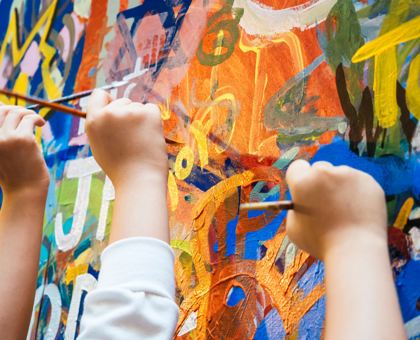 Front View Of Many People Painting On Wall Mural Together
